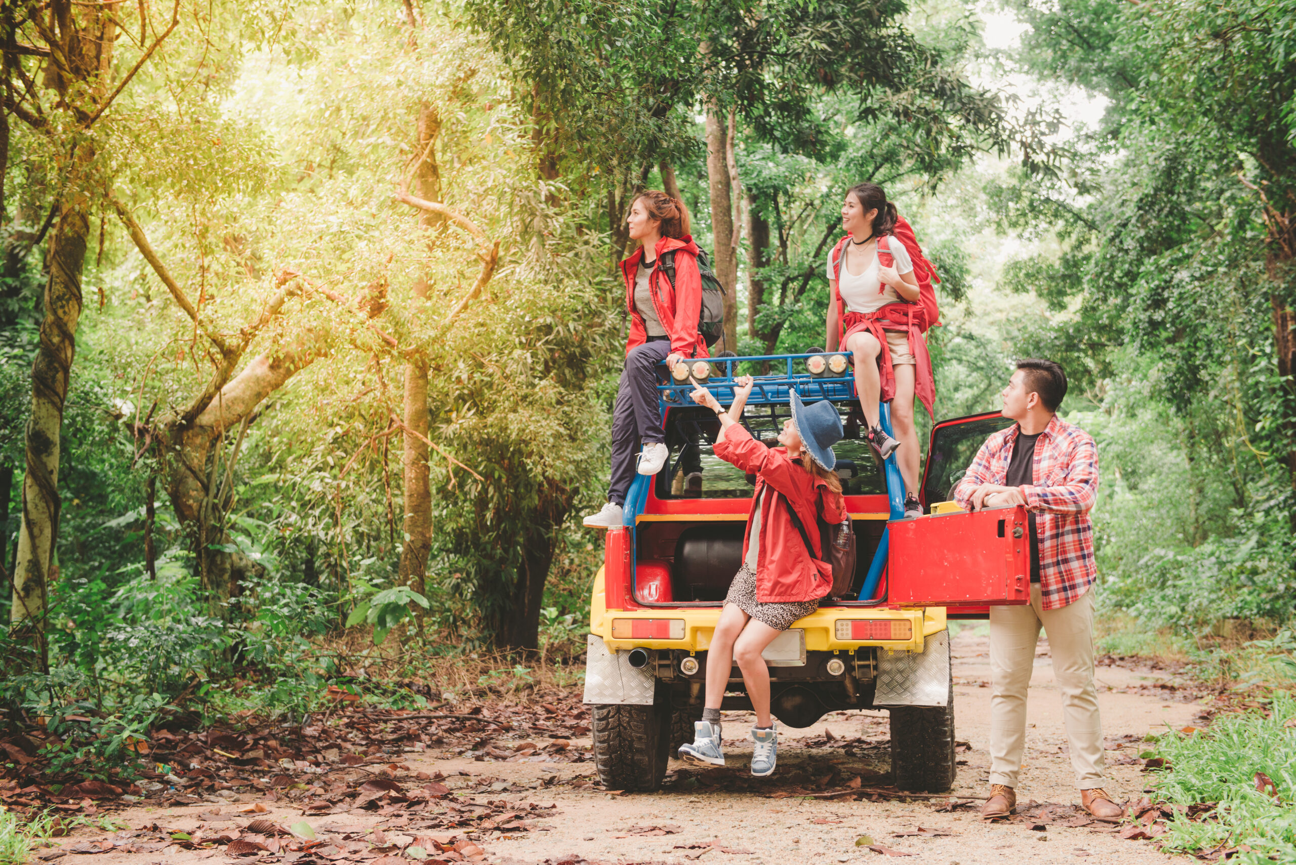 Happy asian young travellers with 4WD drive car off road in forest, young couple looking for directions on the map and another two are enjoying on 4WD drive car. Young mixed race Asian woman and man.